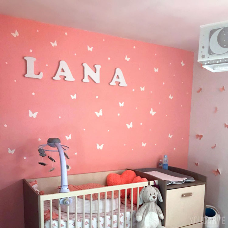 Prénom Lana en lettres découpées en PVC blanc, fixation mousse double-face sur mur de chambre d'enfant.