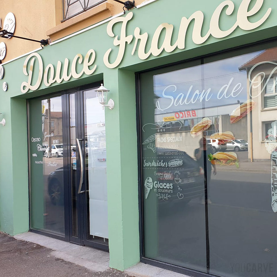 Réalisé par Douce France, enseigne boulangerie-pâtisserie à Jarny, lettres découpées en aluminium-dibond brossé doré (épaisseur 3 mm), fixation sur entretoises avec gabarit de perçage.