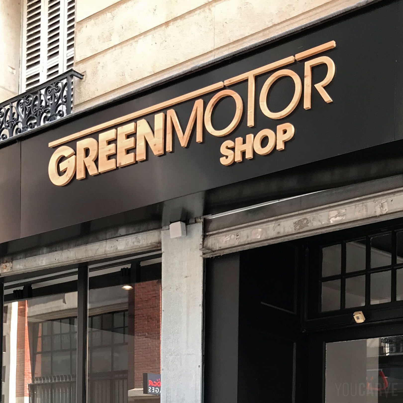 Réalisé par Green Motor Shop à Paris : enseigne showroom magasin de motos, scooters et vélos électriques à Paris, lettres découpées sur-mesure en bois (mélèze épaisseur 19 mm), fixation avec gabarit de positionnement.