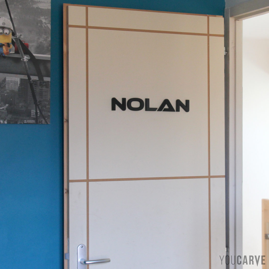 Nolan, prénom d’enfant en relief, lettres découpées en PVC expansé noir ép. 10 mm avec chanfreins, fixation sur porte avec mousse double-face.